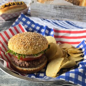 Gluten-free hamburger with gluten-free bun and hot dog in the background on a gluten-free bun