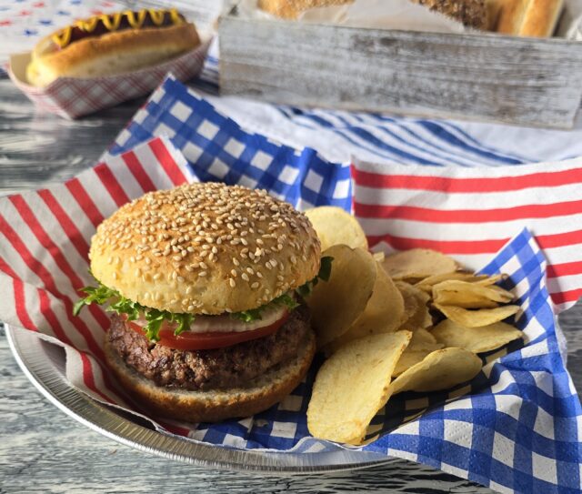 Gluten-free hamburger with gluten-free bun and hot dog in the background on a gluten-free bun