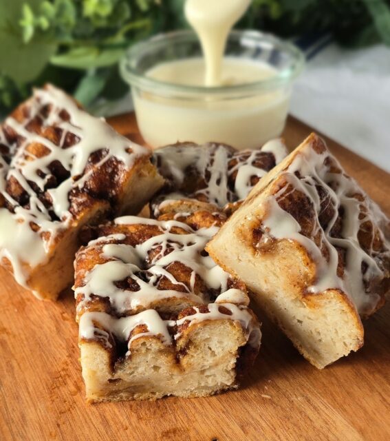 Gluten-free Cinnamon Roll Focaccia with icing drizzle and a bowl of icing